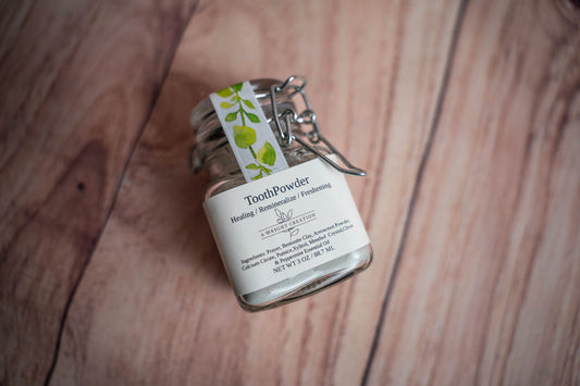 A Wright Creation Healing Tooth Powder in a reusable glass jar with eco-friendly packaging, formulated with bentonite clay, menthol crystals, and natural ingredients to freshen breath, heal, and remineralize teeth, ideal for sensitive oral care.