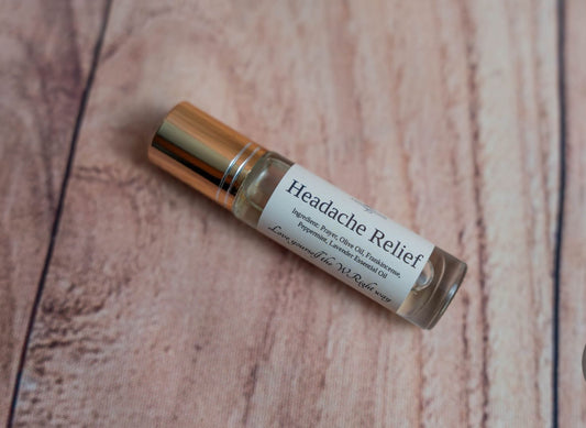 All-natural headache relief essential oil roller with a gold cap, featuring eco-conscious ingredients like olive oil, frankincense, peppermint, and lavender, displayed on a rustic wooden background.